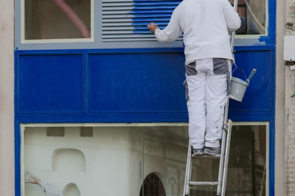 A man painting a window with a ladder